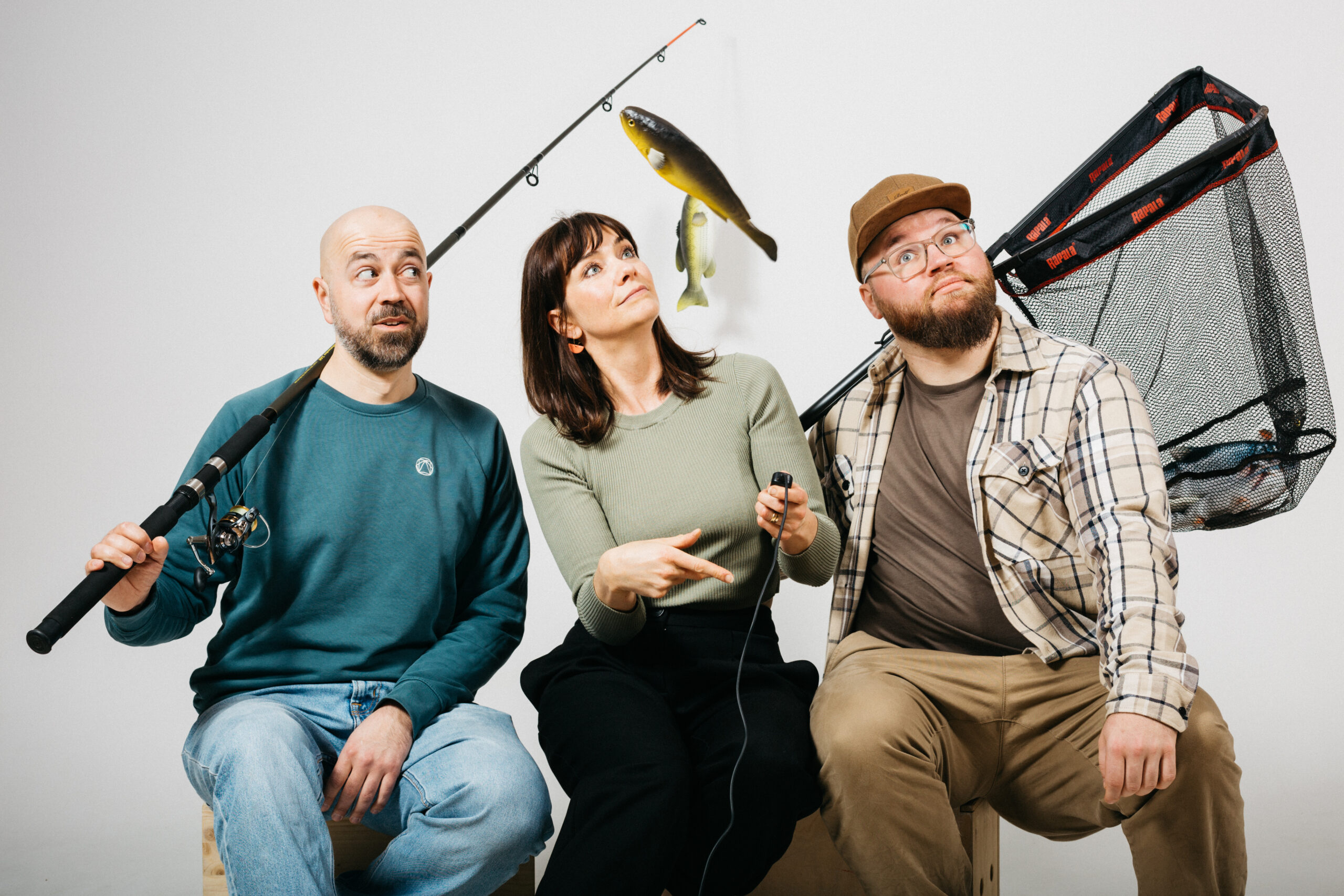 3 people with fishing gear sitting in photo studio